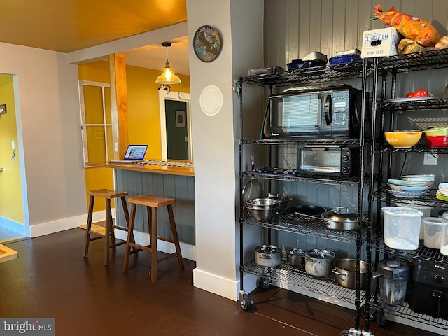 bar featuring black microwave, finished concrete floors, and baseboards