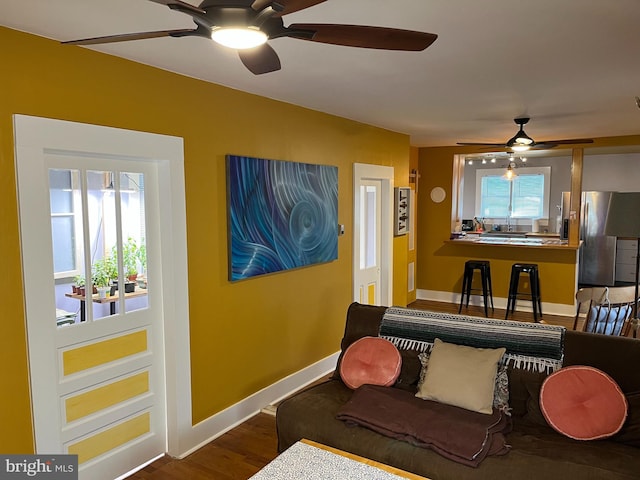 interior space with a wealth of natural light, ceiling fan, baseboards, and wood finished floors