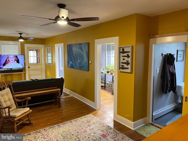 interior space with baseboard heating, wood finished floors, and baseboards