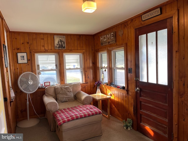 living area featuring carpet and wooden walls