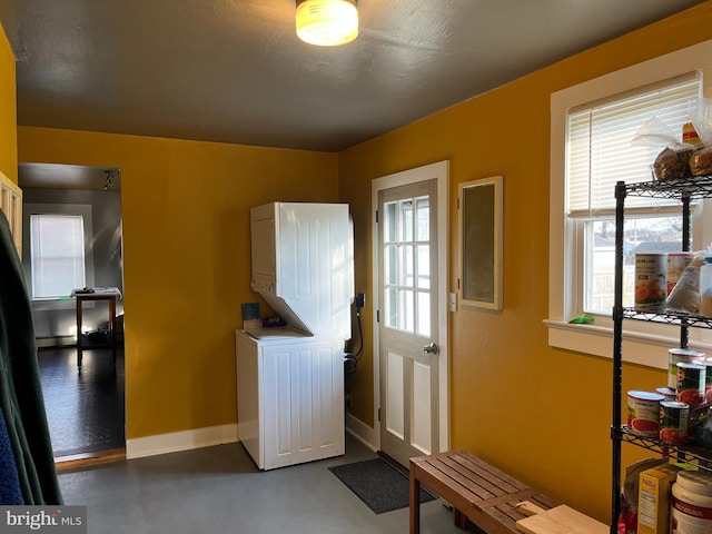 laundry room with laundry area, baseboards, a wealth of natural light, and stacked washer / drying machine