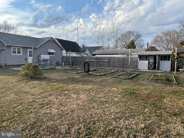 view of yard with a garden, fence, and an outbuilding