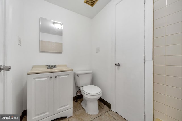 half bath with visible vents, vanity, toilet, and tile patterned floors