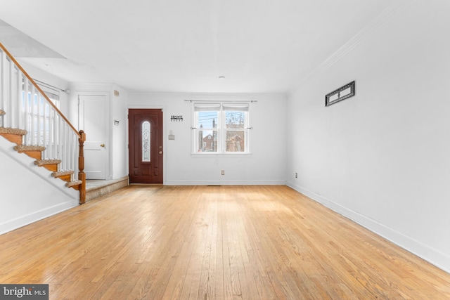 foyer entrance with ornamental molding, light wood-style flooring, baseboards, and stairs