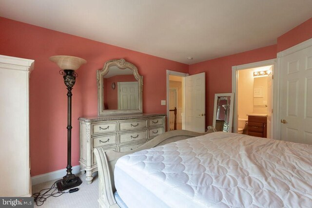 bedroom featuring ensuite bath and baseboards