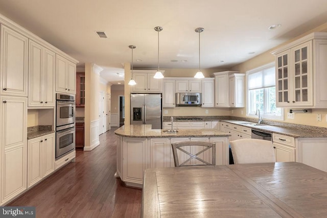 kitchen featuring a sink, appliances with stainless steel finishes, a center island, dark wood finished floors, and glass insert cabinets