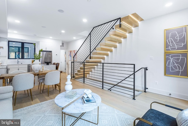 living area featuring light wood finished floors, stairway, baseboards, and recessed lighting