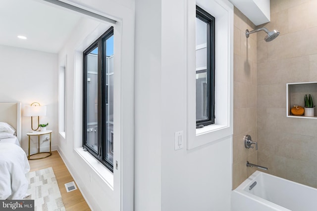 interior space featuring visible vents, ensuite bath, wood finished floors, washtub / shower combination, and recessed lighting