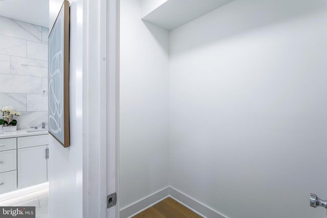 washroom with a sink, baseboards, and wood finished floors