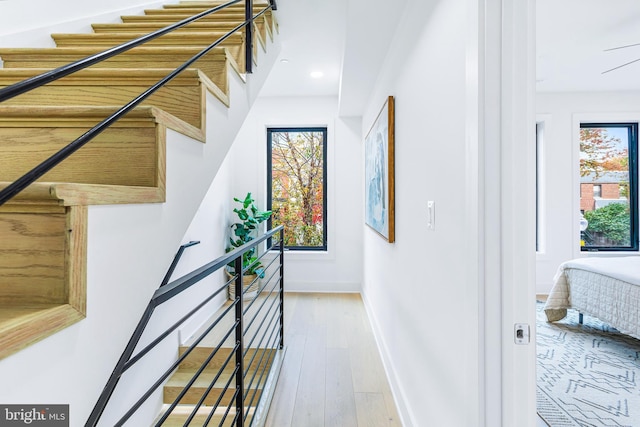 stairway featuring baseboards, wood finished floors, and recessed lighting