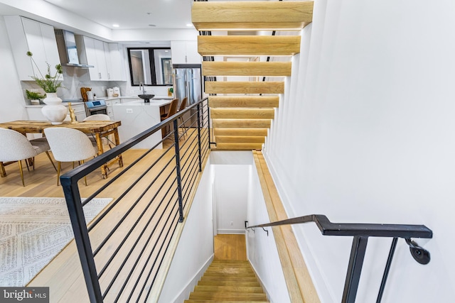 stairs with wood finished floors and recessed lighting