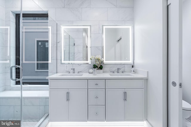 full bathroom featuring a sink, a shower stall, toilet, and double vanity