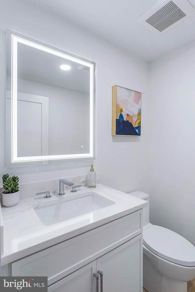 bathroom with visible vents, vanity, and toilet