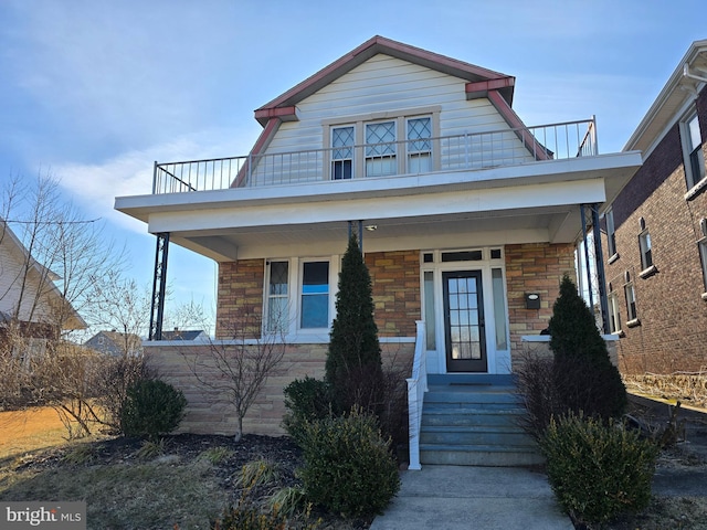 view of front of property featuring stone siding and a balcony