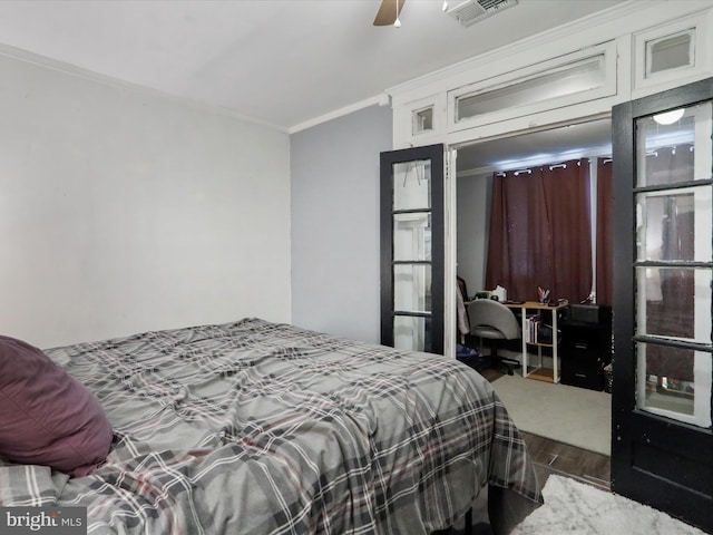 bedroom with a ceiling fan, visible vents, wood finished floors, and ornamental molding