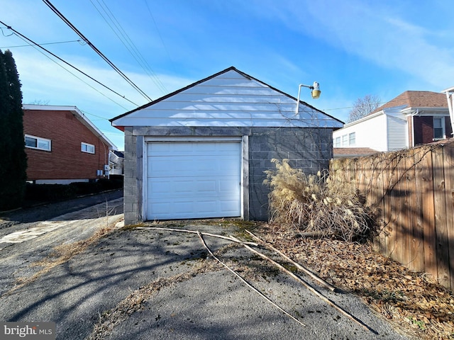 detached garage with aphalt driveway and fence