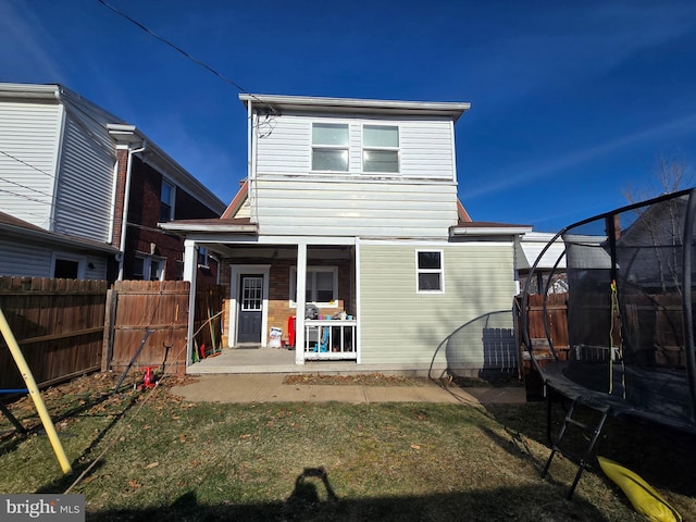 back of house with a patio area, a trampoline, and fence