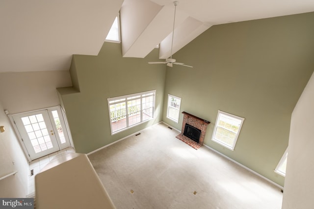 unfurnished living room featuring carpet floors, visible vents, a brick fireplace, ceiling fan, and high vaulted ceiling