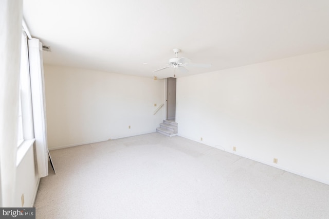 empty room with stairway, carpet flooring, ceiling fan, and visible vents