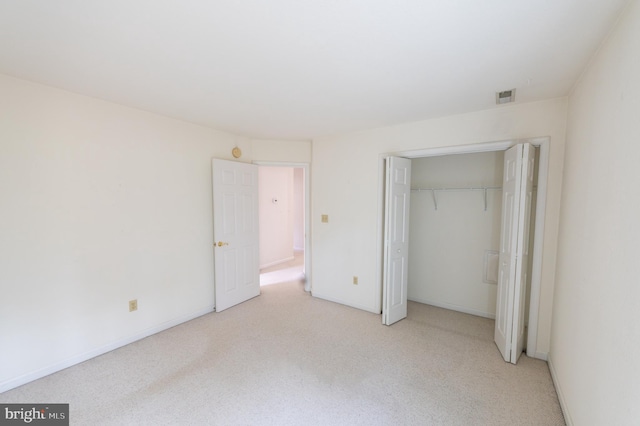 unfurnished bedroom featuring a closet, light colored carpet, visible vents, and baseboards