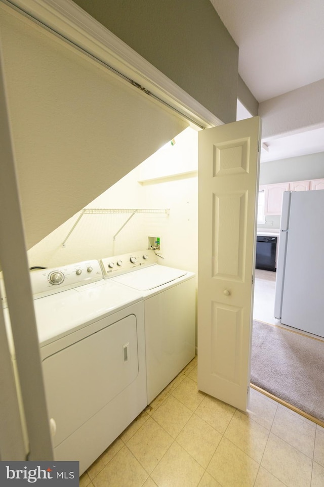 laundry area with laundry area, light carpet, washer and clothes dryer, and light tile patterned floors