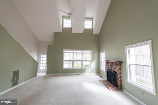 carpeted living room featuring ceiling fan, a towering ceiling, visible vents, baseboards, and a brick fireplace