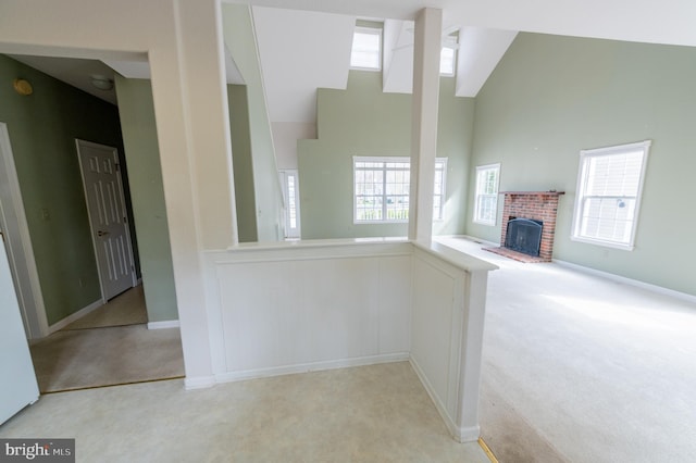 interior space with baseboards, high vaulted ceiling, a fireplace, and light colored carpet