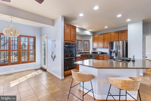 kitchen featuring visible vents, a breakfast bar area, dark stone counters, recessed lighting, and stainless steel appliances