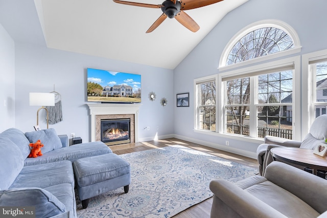 living area featuring baseboards, a fireplace with flush hearth, a healthy amount of sunlight, and wood finished floors