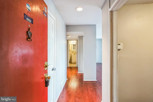 corridor with wood-type flooring and baseboards