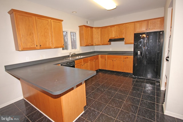 kitchen featuring baseboards, dark countertops, under cabinet range hood, black appliances, and a sink