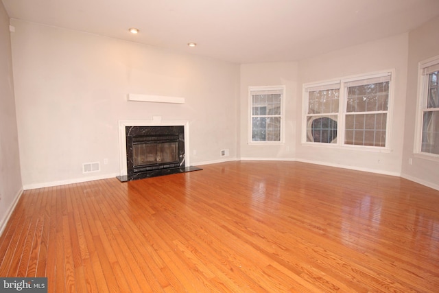 unfurnished living room with baseboards, a fireplace, visible vents, and hardwood / wood-style floors