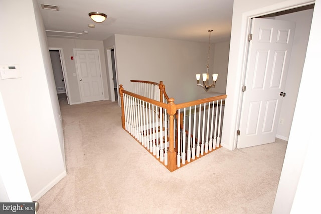 corridor with a chandelier, carpet, visible vents, and baseboards