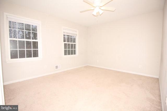 empty room with carpet floors, baseboards, visible vents, and ceiling fan