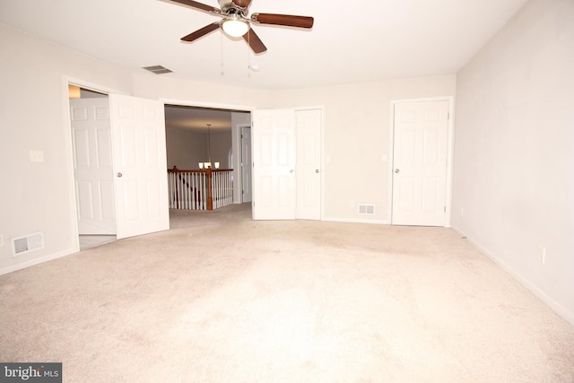 unfurnished bedroom featuring carpet floors, visible vents, and multiple closets