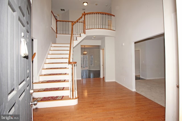 foyer entrance with arched walkways, a high ceiling, wood finished floors, baseboards, and stairs