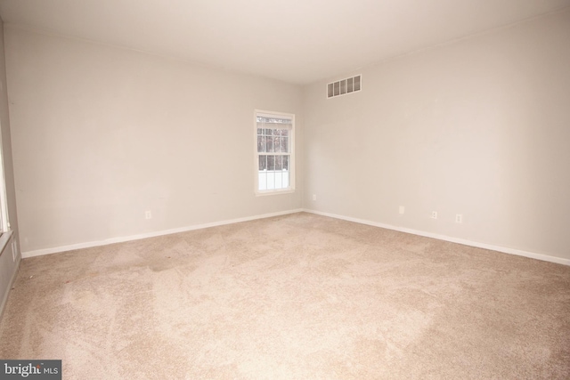 empty room featuring carpet floors, baseboards, and visible vents