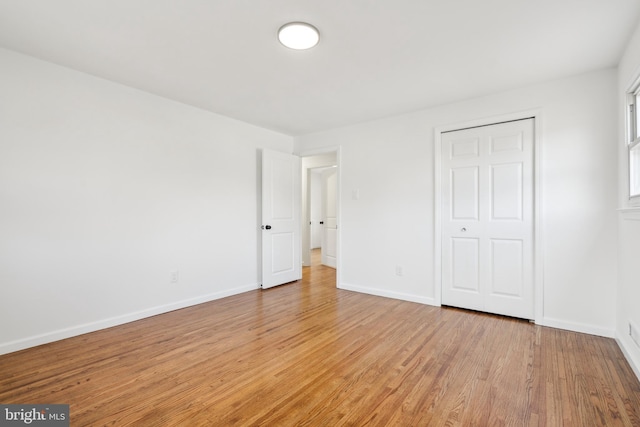 unfurnished bedroom featuring baseboards, a closet, and light wood-style floors