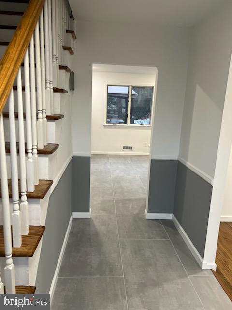 hallway with stairway, baseboards, and tile patterned floors