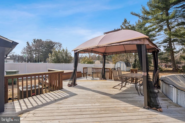 wooden deck featuring a shed, an outbuilding, a fenced backyard, and a gazebo