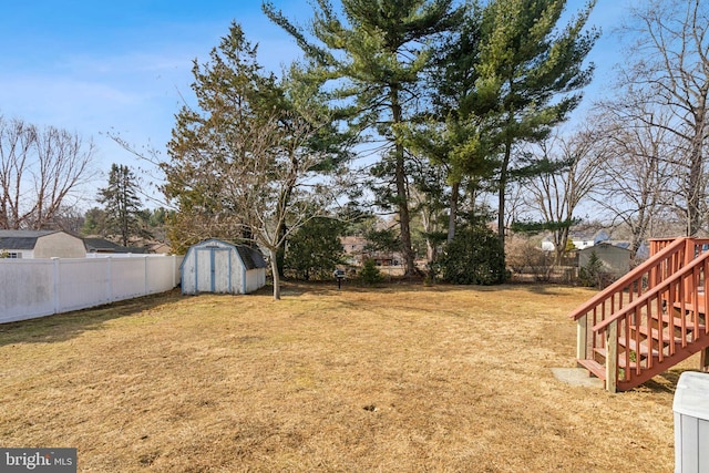 view of yard featuring a fenced backyard, stairs, a storage unit, and an outdoor structure