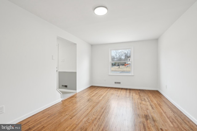 spare room featuring visible vents, baseboards, and wood finished floors