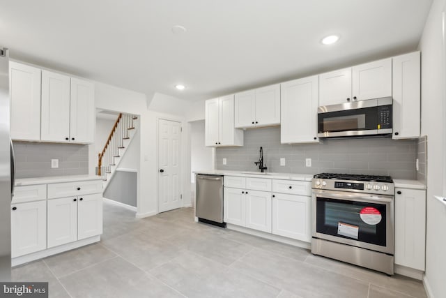 kitchen with light tile patterned floors, white cabinets, stainless steel appliances, light countertops, and a sink