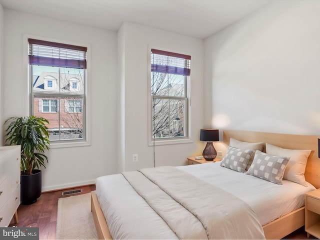 bedroom with wood finished floors, visible vents, and baseboards