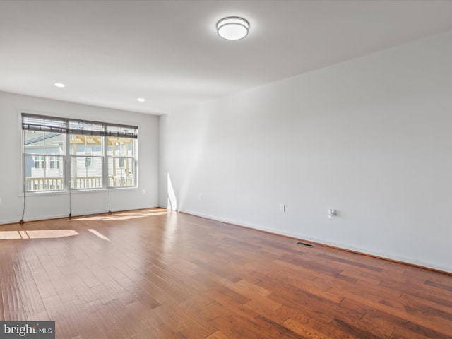 spare room featuring recessed lighting, wood finished floors, visible vents, and baseboards