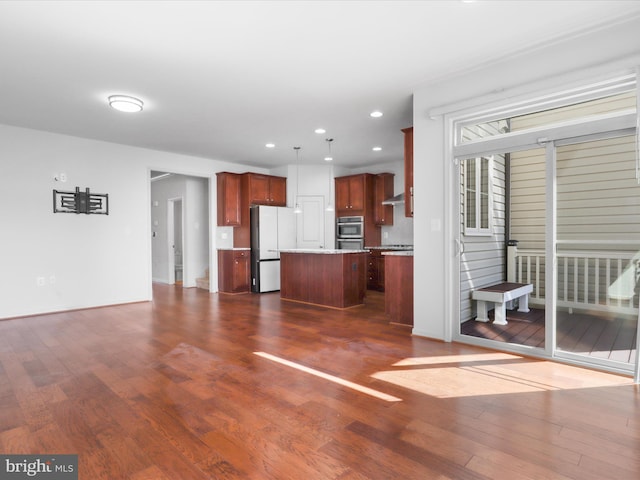 kitchen featuring dark wood-type flooring, freestanding refrigerator, a kitchen island, and stainless steel double oven