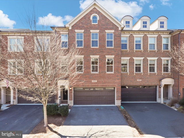 townhome / multi-family property featuring brick siding, driveway, and an attached garage