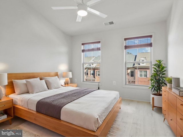 bedroom with a ceiling fan, light wood-type flooring, visible vents, and baseboards