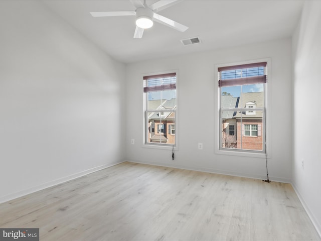 empty room featuring light wood-style floors, visible vents, baseboards, and a ceiling fan