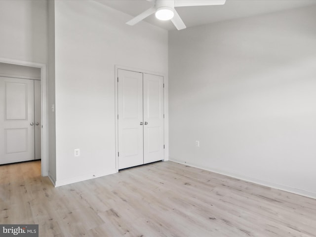 unfurnished bedroom featuring light wood-style floors, a closet, baseboards, and a ceiling fan